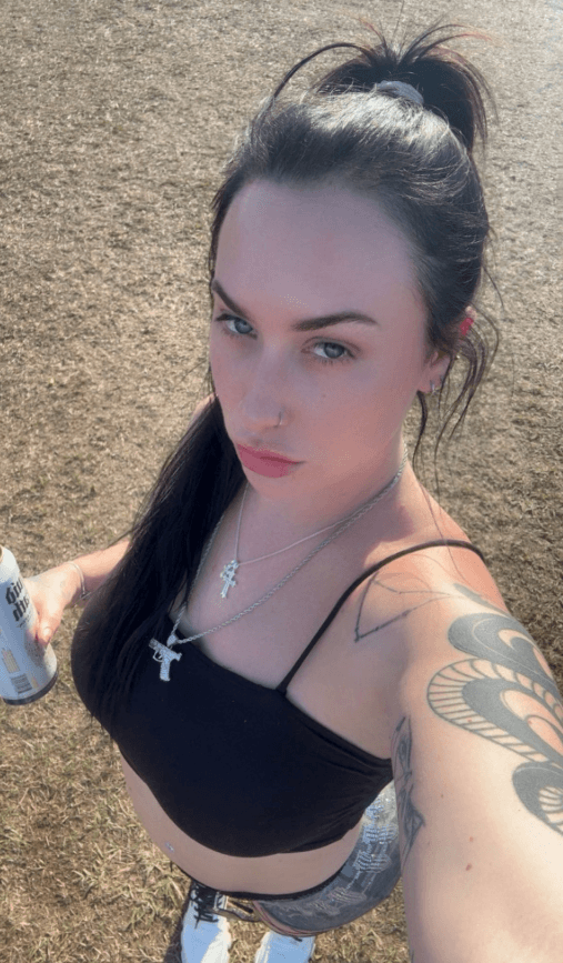Goth OnlyFans model Stassie outdoors in a black crop top with cross necklaces and arm tattoos