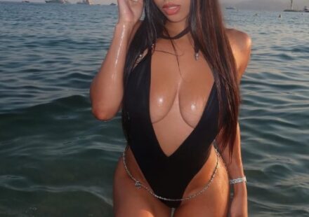 Autumn Falls, a Puerto Rican OnlyFans star, in a black plunge swimsuit and hat in the ocean